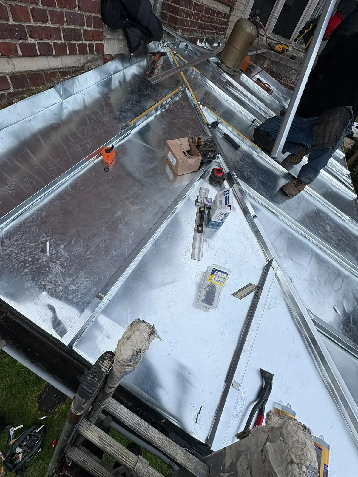 Travail de zinguerie sur une noue, feuilles de zinc en cours de pose