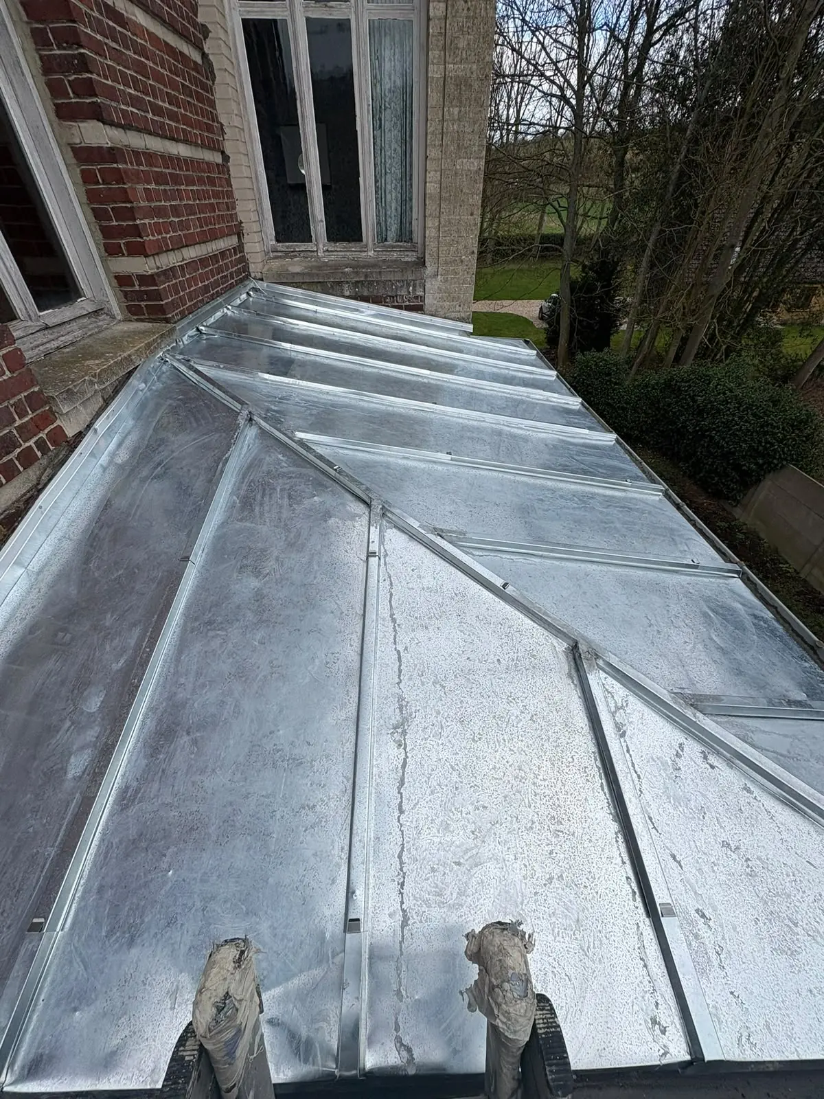 Pose de feuilles de zinc sur un pan de toiture à faible pente